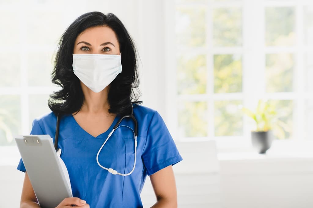 profissionais de saúde_Por insidecreativehouse_caregiver-in-blue-uniform-face-mask-against-corona-2021-12-09-20-04-33-utc