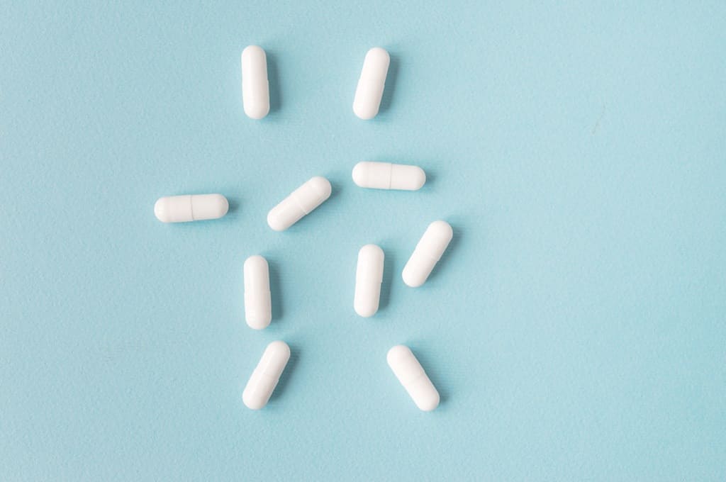 medicamentos_Por olenasvechkova_ENVATO_HN_white-capsule-pills-on-a-blue-background-2023-11-27-04-54-42-utc