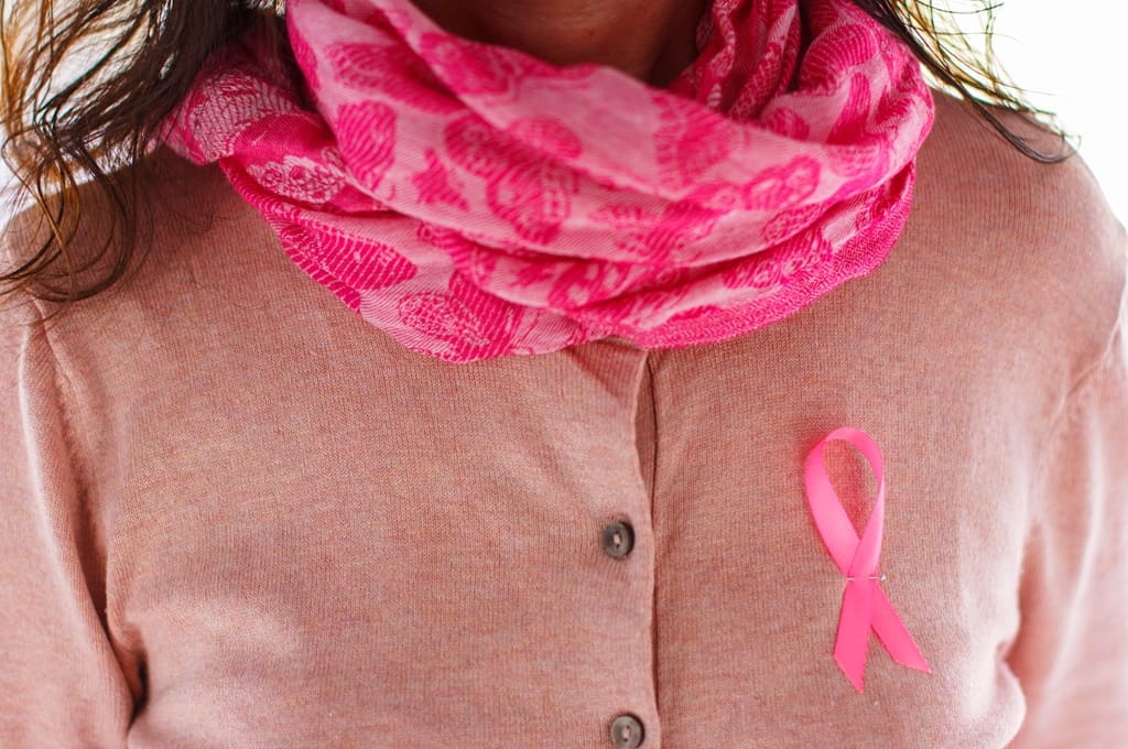 cancro da mama_Por LeaMallo_ENVATO_HN_woman-with-a-pink-cardigan-and-a-pink-ribbon-brea-2023-11-27-05-30-04-utc