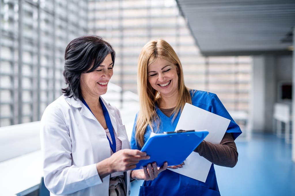 profissionais de saúde_Por halfpoint_ENVATO_HN_women-doctors-standing-in-corridor-on-medical-conf-2023-11-27-05-35-58-utc